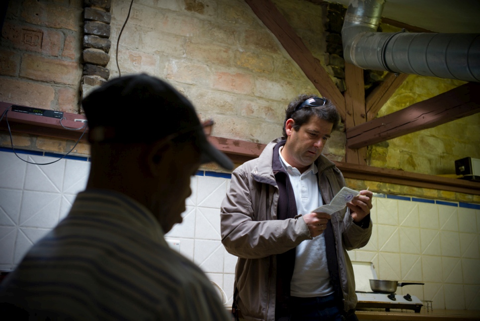 Social worker Andras Rakos speaks to an asylum-seeker about his residency papers at a shelter for homeless people and refugees in Budapest. © UNHCR/Bela Szandelszky