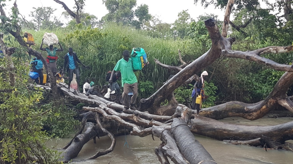 South Sudanese refugees use a tree branch to cross the Kaya River into Uganda. © UNHCR/Massoumeh Farman-Farmaian 