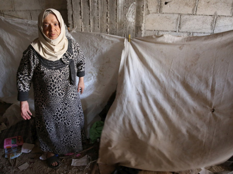 Aisha stands in the middle of an unfinished apartment turned into shelter for internally displaced people in the hard-to-reach town of Qudsaya, Syria. © UNHCR/Qusai Alazroni