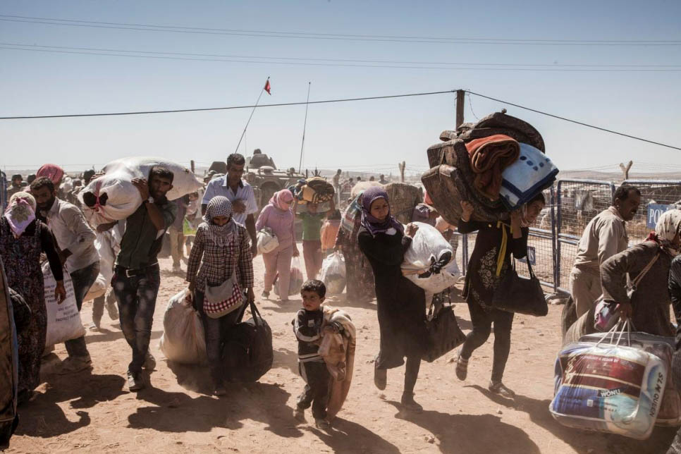Syrian Kurdish refugees cross into Turkey near the town of Kobani, Syria, in this September 2014 file photo. © UNHCR/Ivor Prickett