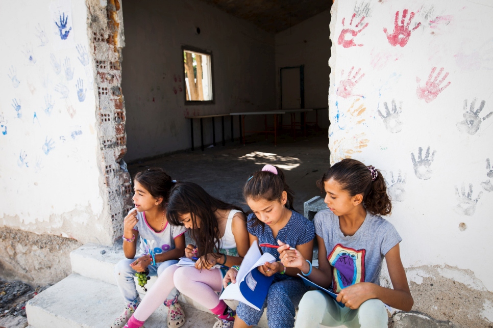 Young refugee girls sit on the steps of an informal recreational space at a camp in Lagkadikia, northern Greece where more than 30 per cent of the population are children. UNHCR and its partners have created a safe space for unaccompanied children here. © UNHCR/Achilleas Zavallis