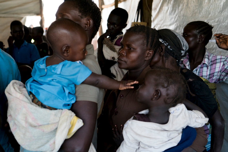Sidah Hawa fait la queue avec ses enfants au centre de transit de Kuluba pour l’enregistrement et faire vacciner ses enfants. © HCR / Michele Sibiloni