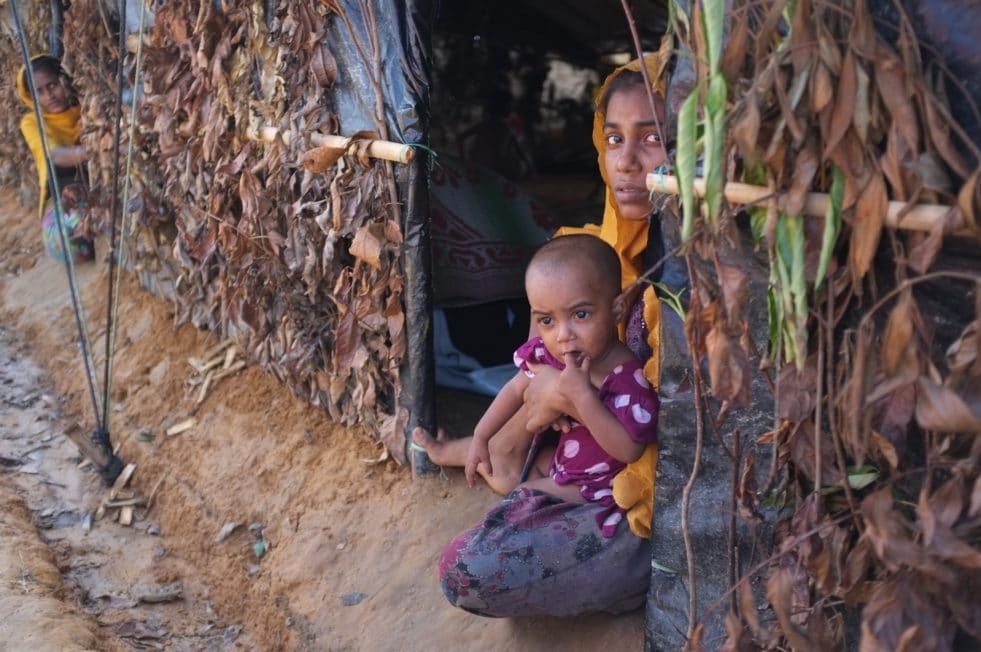 A Rohingya refugee from Rathedaung, Myanmar holds her child in a makeshift shelter at the Kutupalong extension site. ; As hundreds of thousands of Rohingya sought safety in Bangladesh between late-August and late-September 2017, UNHCR began work on an extension site next to the long-established Kutupalong refugee camp in Cox’s Bazar. Whole families, young mothers and unaccompanied minors were among those fleeing for their lives since fighting reignited in Myanmar. They came by boat or walked barefoot for days, leaving most of their possessions behind. Large groups crossed into south-eastern Bangladesh hungry, in poor physical condition and in need of life-saving support. By mid-September, the Bangladeshi Government allocated some 2,000 acres of land, on which family tents and temporary communal shelters were erected to shelter new arrivals. UNHCR site planners estimate that these will be sufficient to house 150,000 of the estimated 480,000 people who have arrived in Bangladesh.