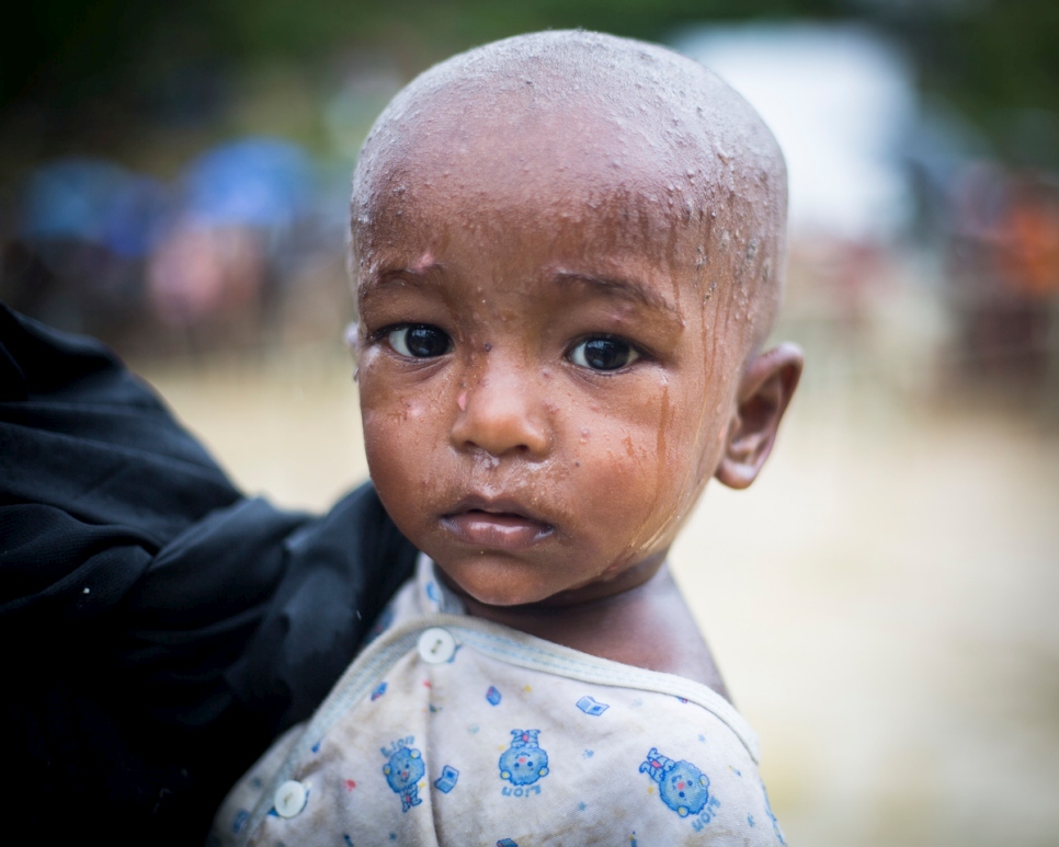 A Rohingya baby and his mother queue for an aid distribution in rainy Kutupalong refugee camp, near Cox’s Bazar, Bangladesh. © UNHCR/Roger Arnold