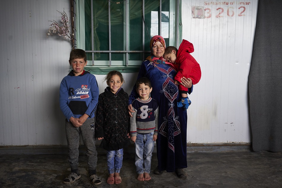 Zeenab, 33, who is eight-months pregnant, holds her two-year-old son Mohamed as she poses for a photograph with her son Murad, 11, left, daughter Rahaf, 7, son Laith, 4, at their shelter in Zaatari camp, Jordan. © UNHCR/David Azia