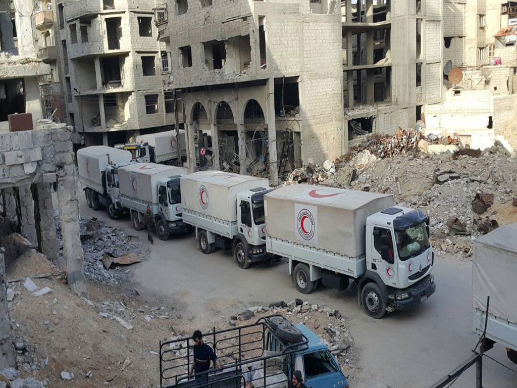 A humanitarian aid convoy enters the besieged Syrian enclave of Eastern Ghouta , bringing relief to the 393,000 civilians trapped there. © UNHCR/Sajjad Malik