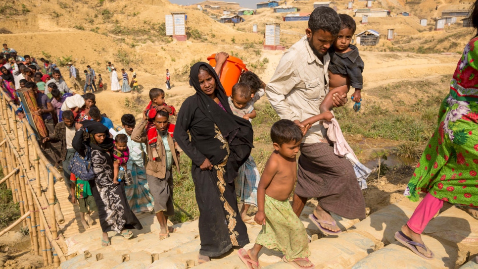 Mohammad Harez and Momena Begum trek with their children to a new shelter on high ground in Kutupalong refugee settlement, Bangladesh. © UNHCR/Roger Arnold