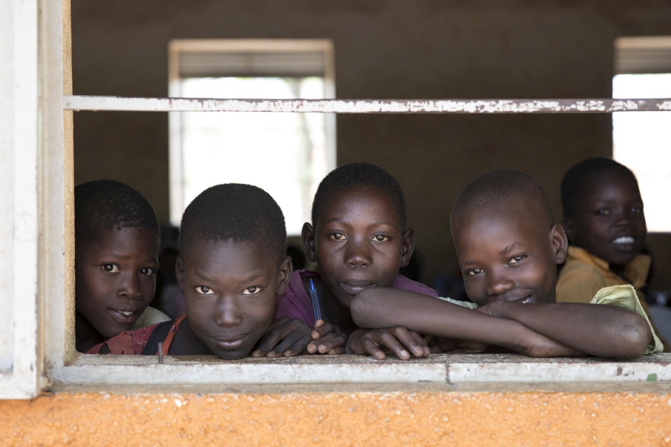 five young sudanese boys looking out a window