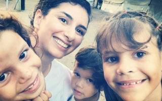 A selfie with four smiling people, cropped tightly. There are three children and one adult woman.