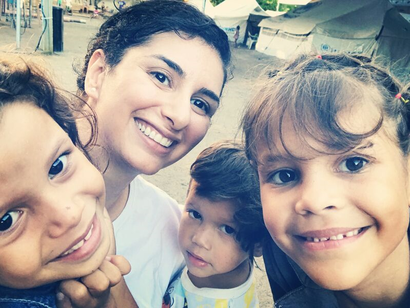 A selfie with four smiling people, cropped tightly. There are three children and one adult woman.
