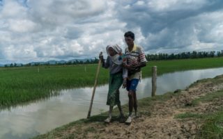 two refugees walking barefoot along a lakeshore