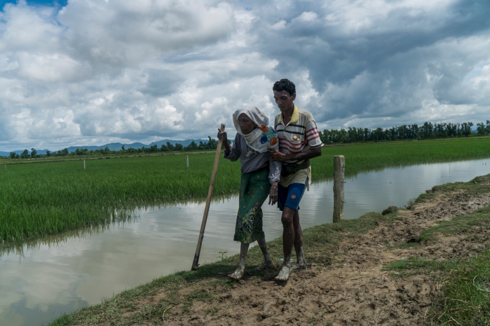 two refugees walking barefoot along a lakeshore