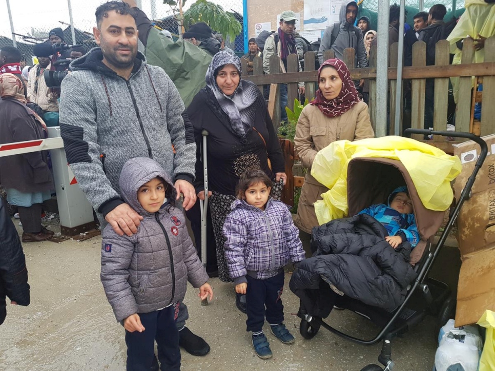  une famille syrienne pose devant une foule de demandeurs d'asile partant des îles grecques