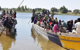 refugees in two motorized canoes on a river