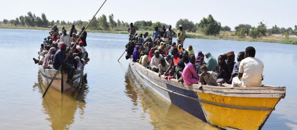 refugees in two motorized canoes on a river