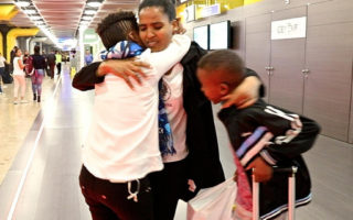 a mother embraces her two young sons in an airport