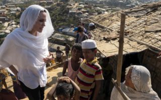 Lady in a white head scarf speaks with children and another lady with a headscarf on