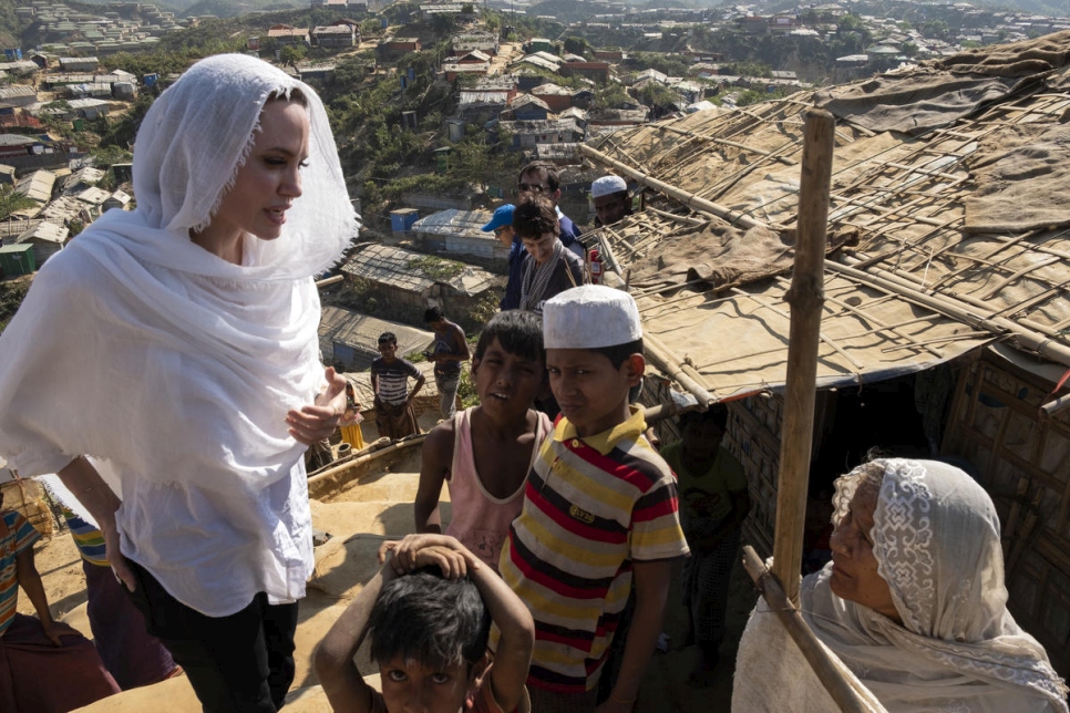 Lady in a white head scarf speaks with children and another lady with a headscarf on