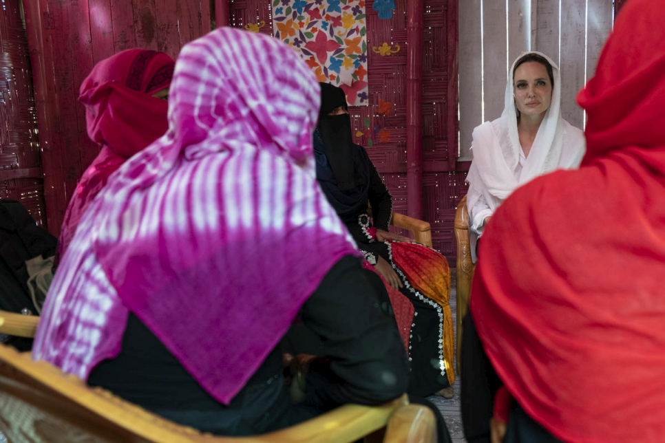 Five women in a head scarves sit in a circle having a conversation