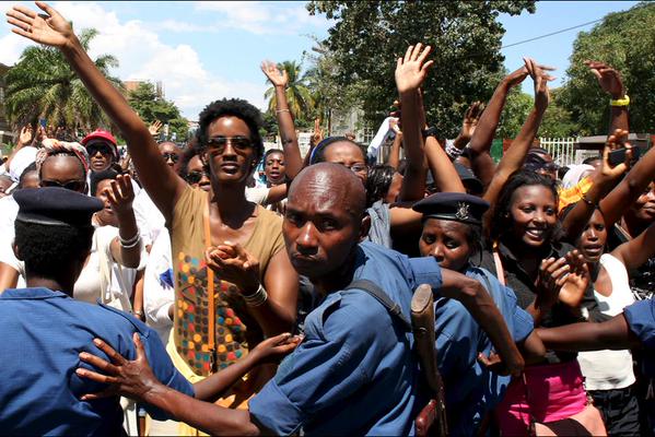 a crowd of women being held back by a human chain of police officers