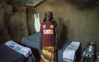 A woman stands in an open room smiling at the camera