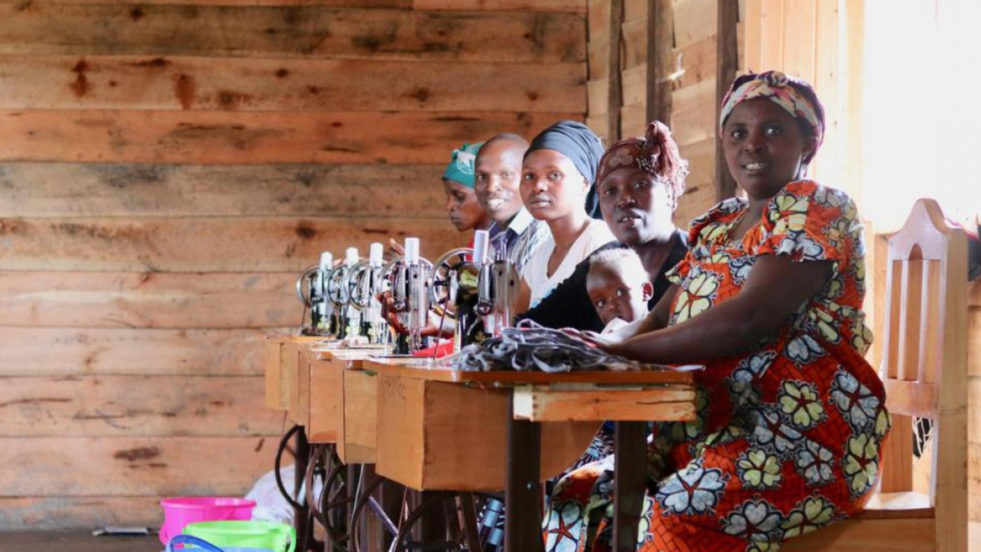 Five women sitting in a row making soap