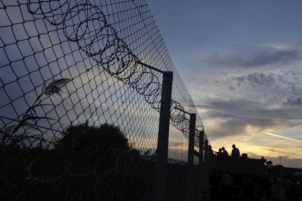 Image of Hungarian border amidst a sunset with people in the distance