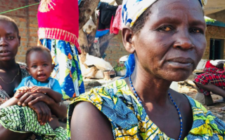 A woman from the DRC sits somberly looking into the camera