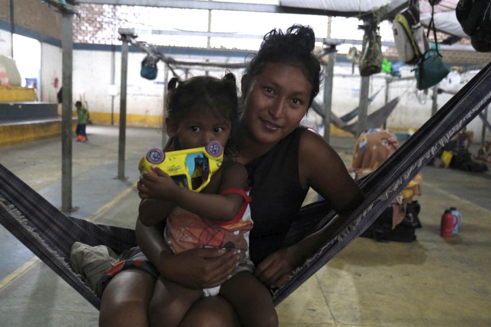 A woman and child, both Venezuelan refugees, sit on a hammock