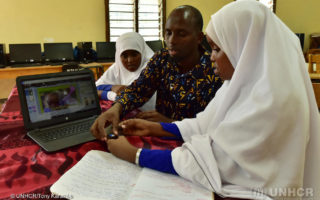 A Somali man sits beside a Somali woman and teaches her something for the computer