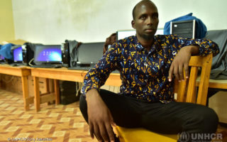 Somali man sits on a chair in front of computers