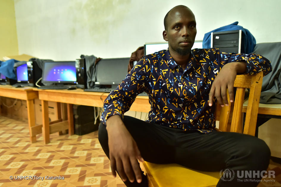 Somali man sits on a chair in front of computers