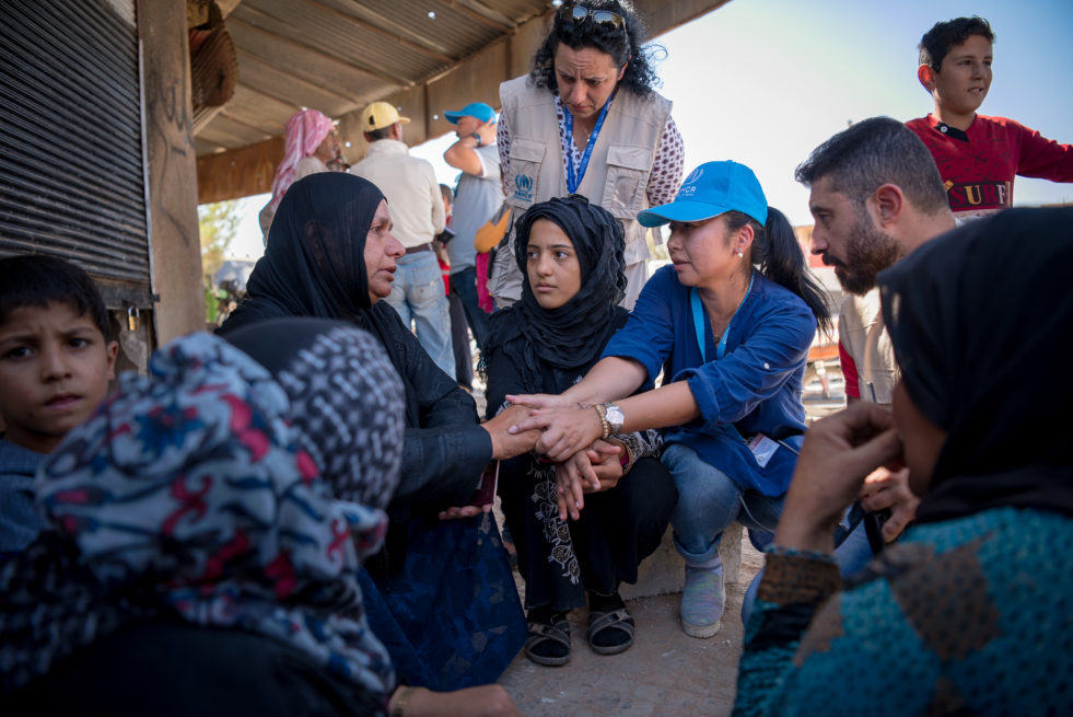 Humanitarian aid worker holds a distraught woman's hand as she listens to her story