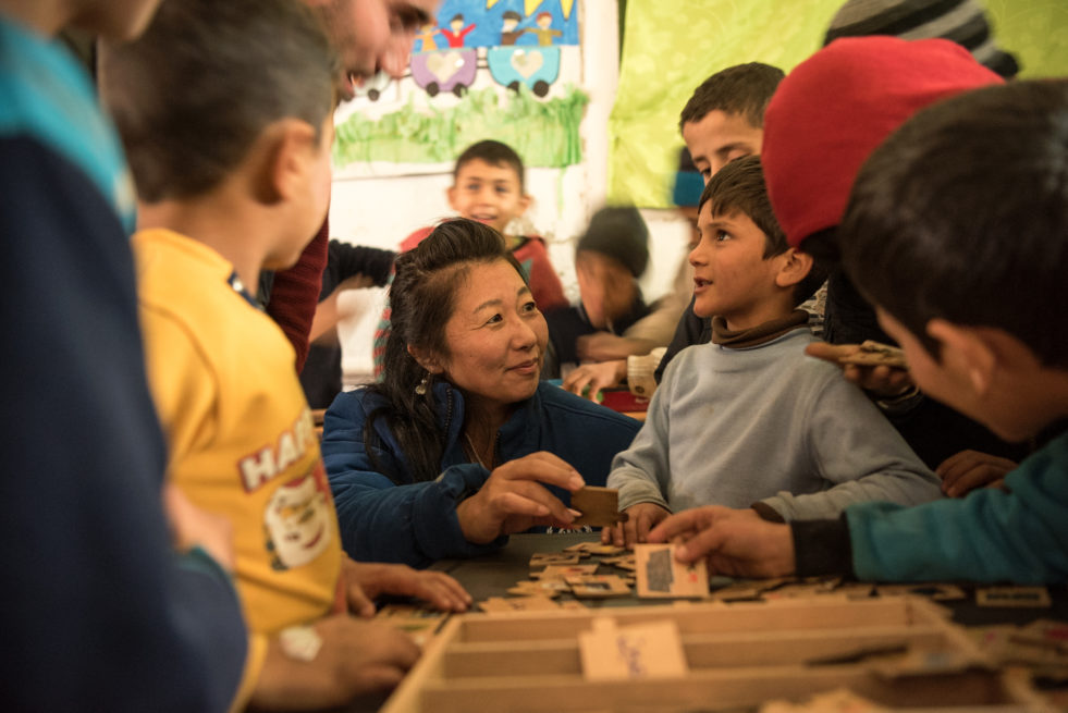 Humanitarian aid worker spends time meeting refugee children in a classroom