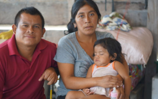 A Venezuelan mother holds her child and sits beside her husband