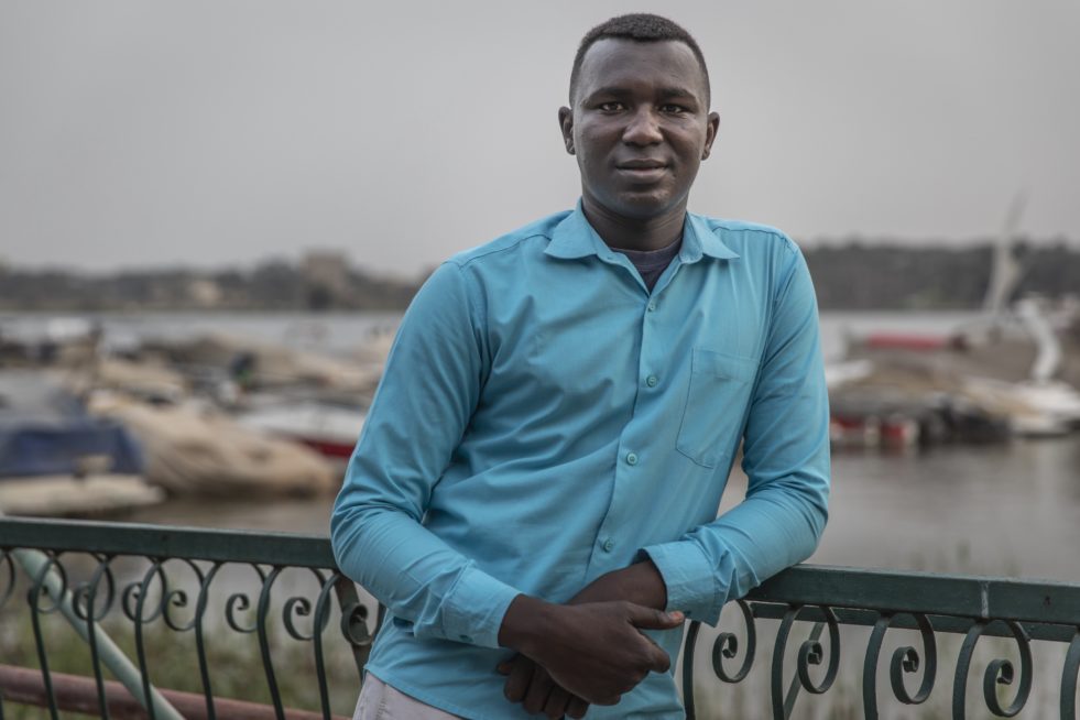 Portrait of a young refugee climate change activist posing in front of a harbour
