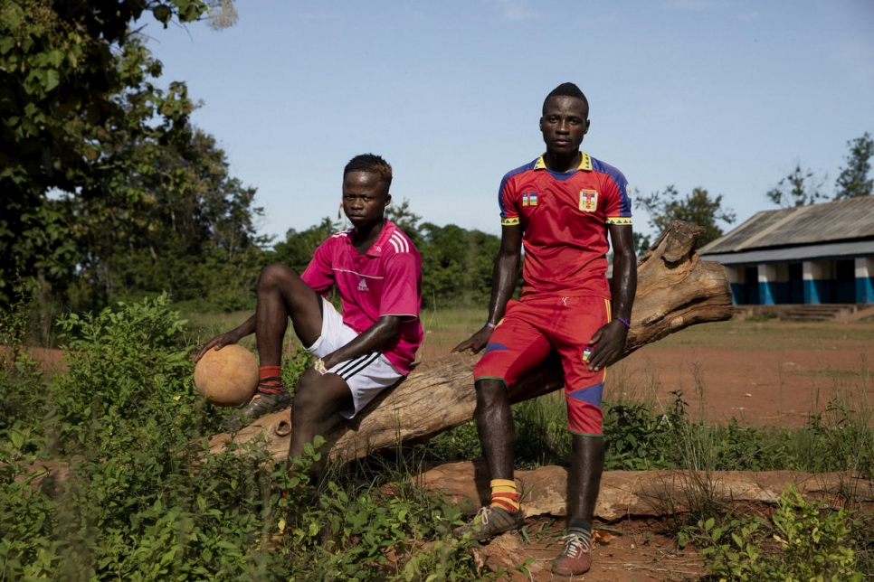 Two Central African men pose on a log for a portrait