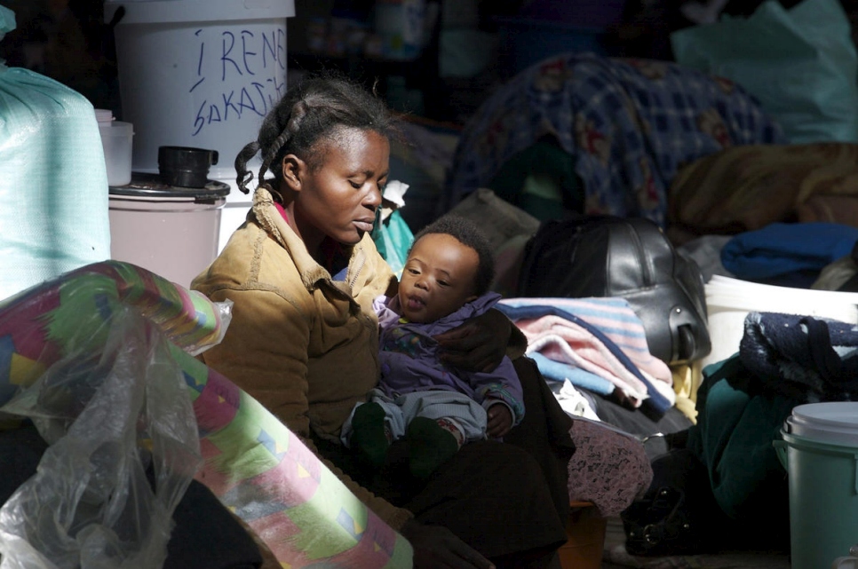 Mother holds child among clutter in South Africa
