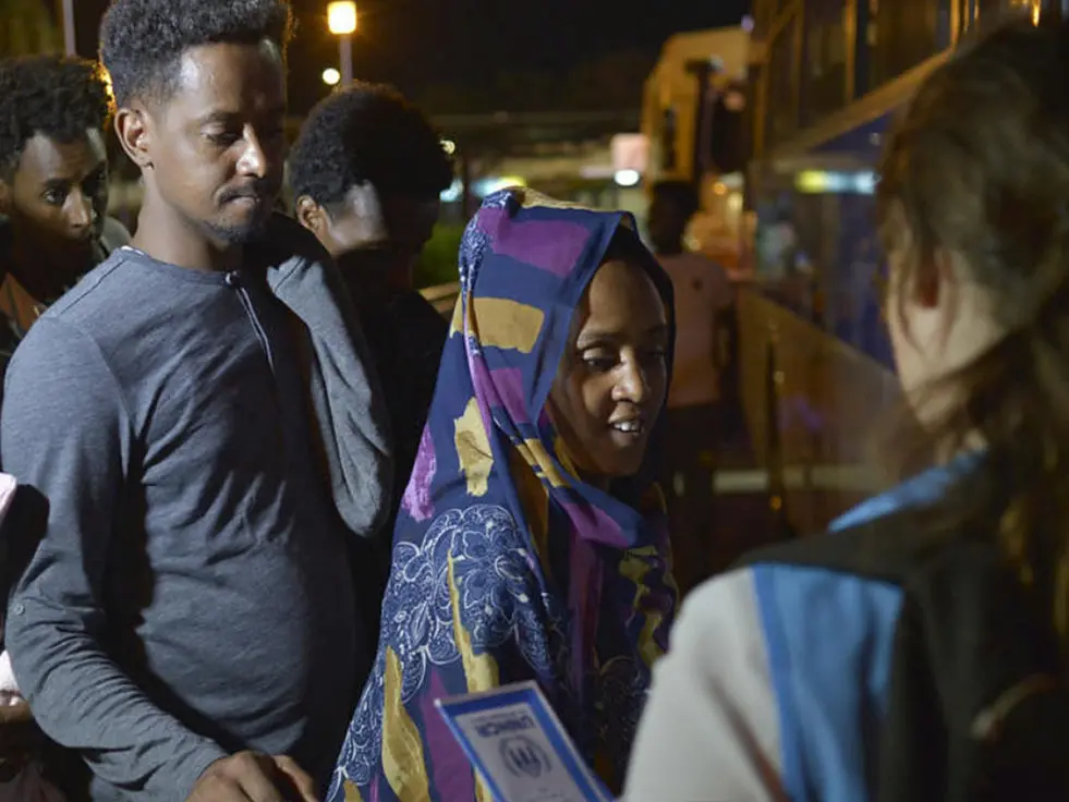 A man and a woman wait to get onto a bus in Libya