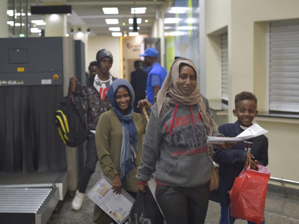 Two smiling refugees from Libya arrive at an airport in Rwanda