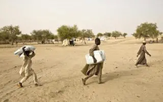 Three refugees from Nigeria cross a desert