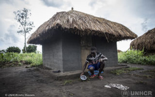 Young boy from South Sudan places a solar lamp outside of his home to charge it so that he could study as he strives to continue his education