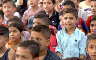 A boy sits in a crowd of children in Lebanon