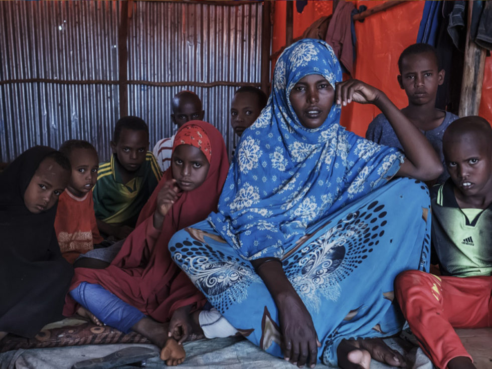 Somali woman sits in a room surrounded by her children