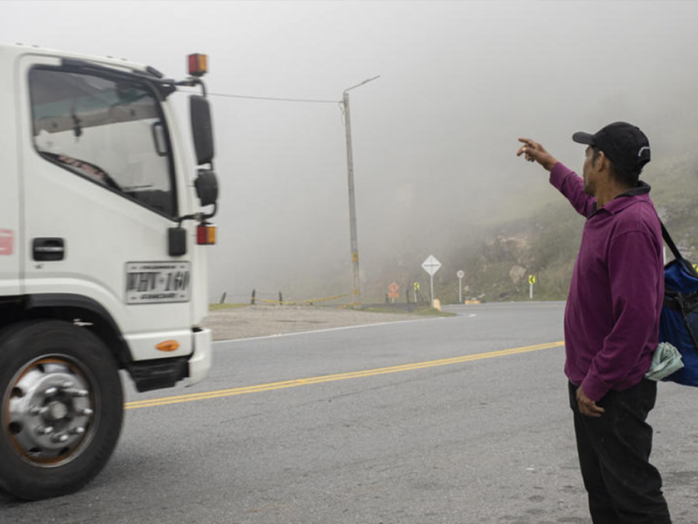 A hitchhiking Venezuelan man attempts to hail down a large truck