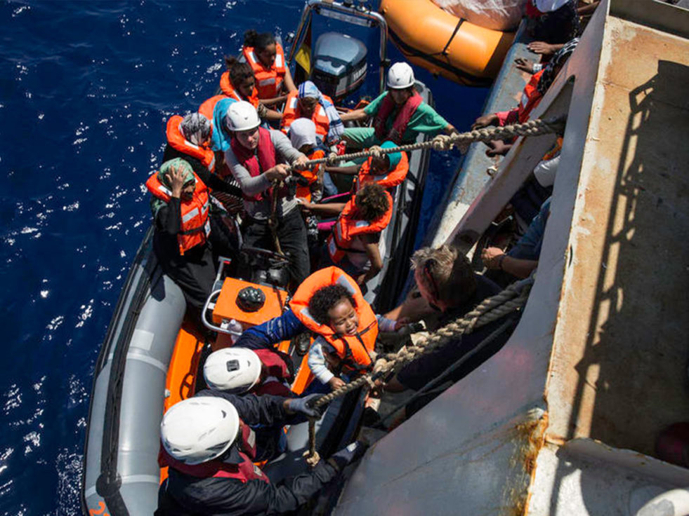 People try to climb onto a boat