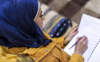 A woman works on her education by writing in a notebook in Lebanon