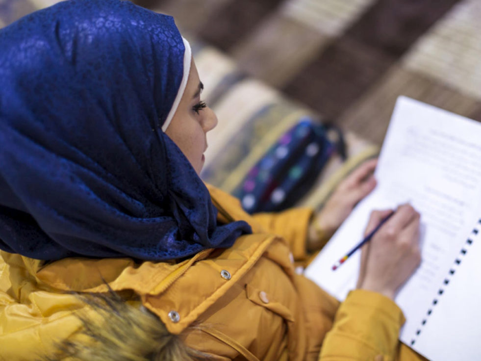 A woman works on her education by writing in a notebook in Lebanon