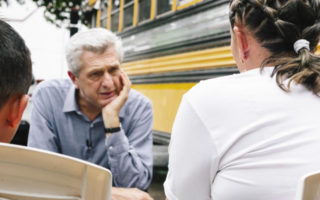 Fillipo Grandi talks to a young girl besides a school bus in Mexico