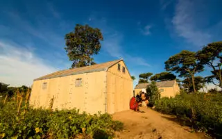 People crouched outside of two Refugee Housing Units